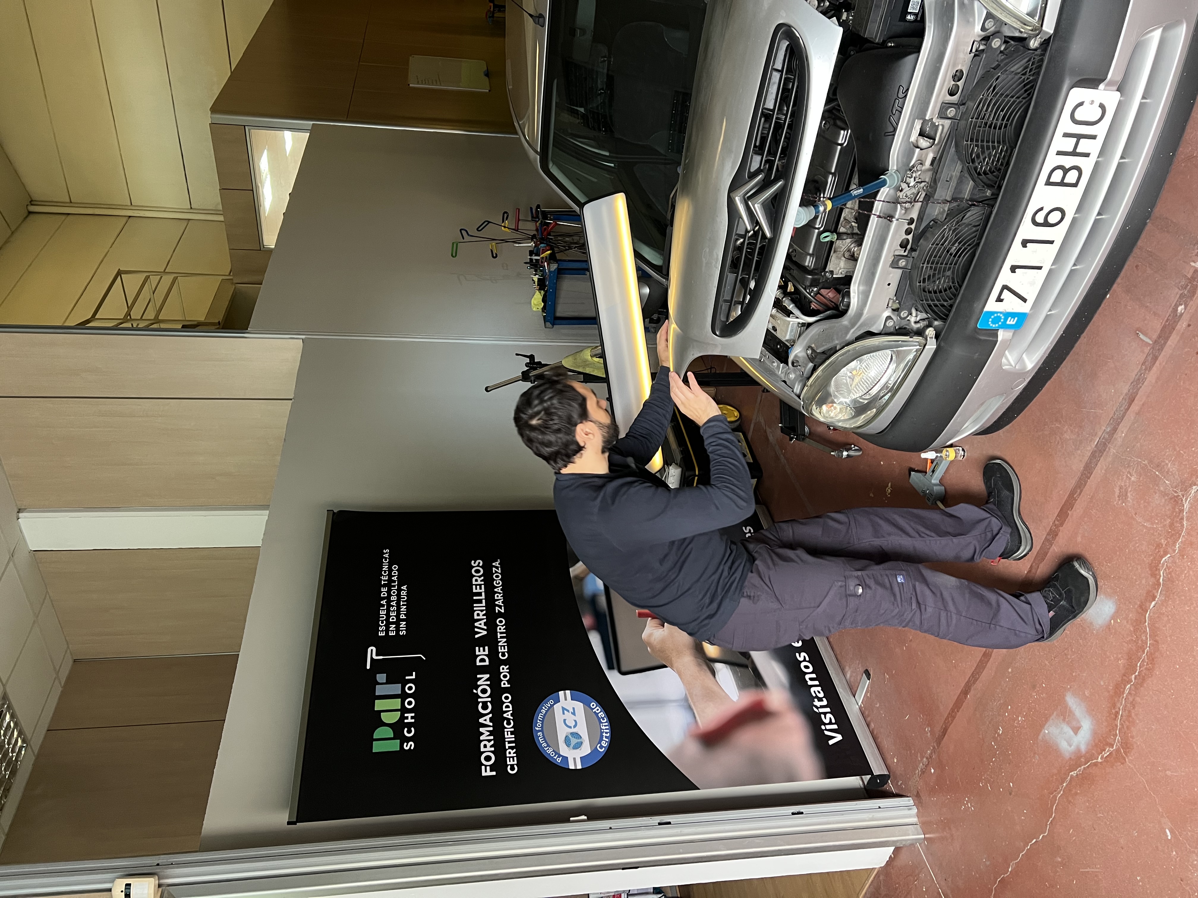 Alumno reparando el capó de un coche con lámpara PDR en las instalaciones de PDR School
