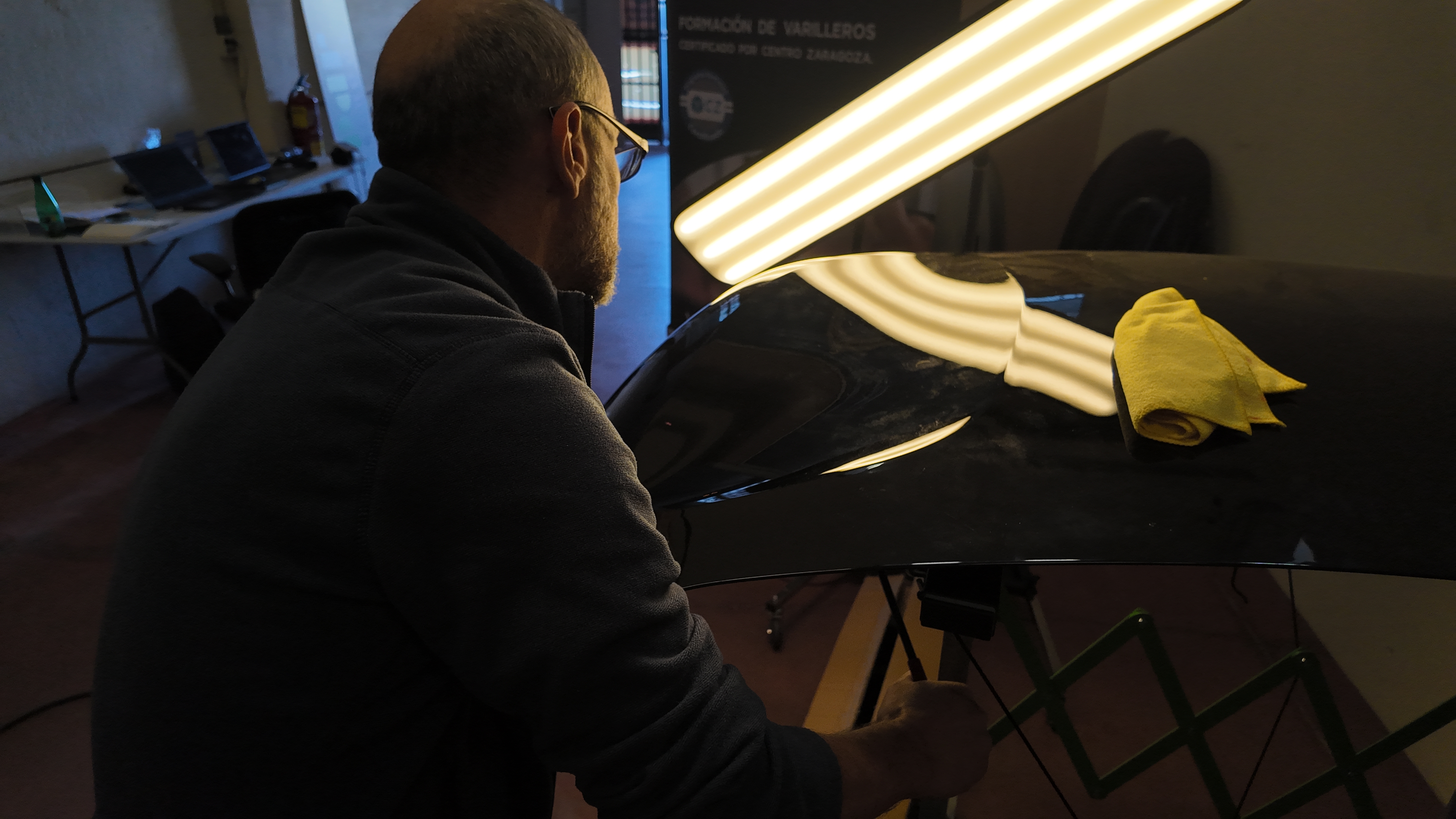 Formador revisando un capó bajo la lámpara de reflejo en el aula de PDR School