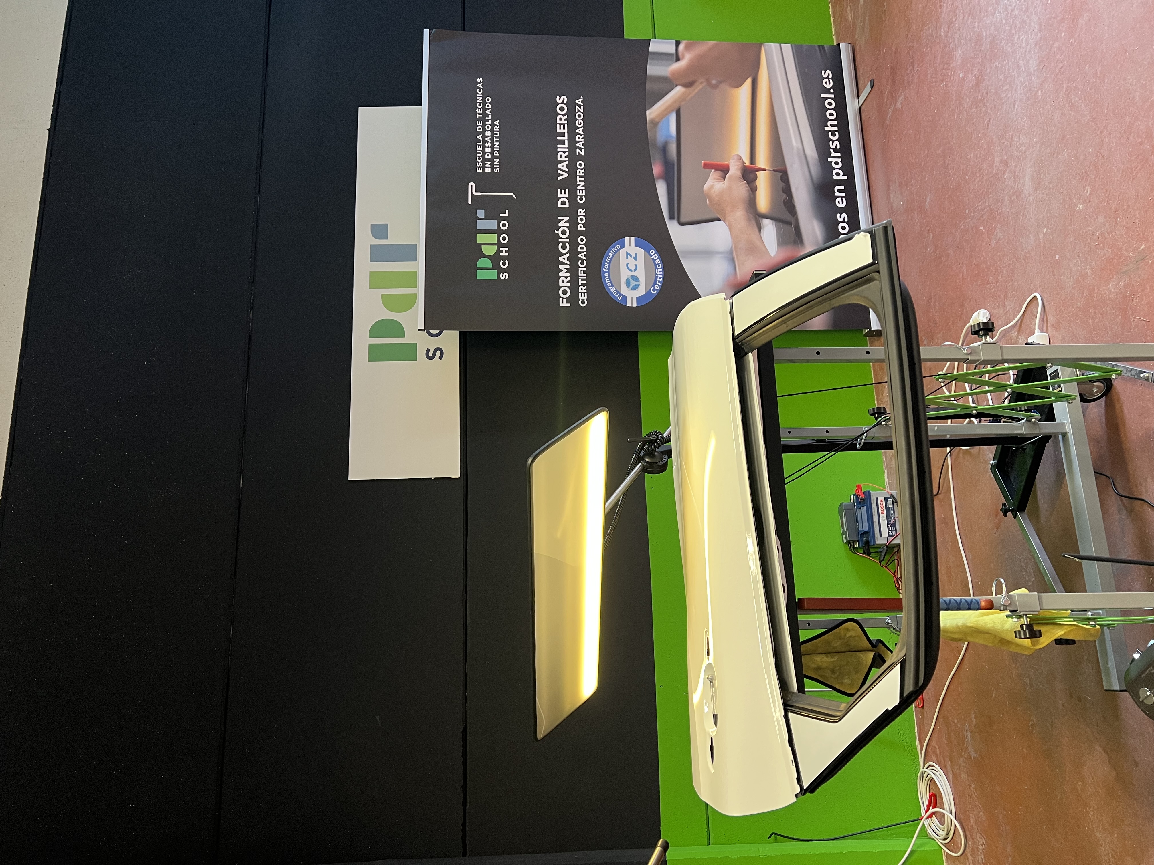 Puesto de prácticas con puerta de coche y lámpara PDR junto al cartel de PDR School